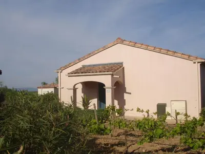 a small white house with an archway and bushes at Holiday Home VILLA T3 PMR ZWISCHEN NARBONNE UND CARCASSONNE by Interhome in Homps