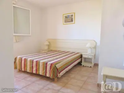 a bedroom with a bed with a striped bedspread and a table at Holiday Home VILLA T3 PMR ZWISCHEN NARBONNE UND CARCASSONNE by Interhome in Homps