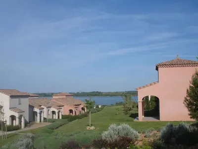 a row of houses on a hill next to a lake at Holiday Home VILLA T3 PMR ZWISCHEN NARBONNE UND CARCASSONNE by Interhome in Homps