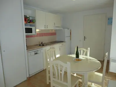a kitchen with a table and chairs and a bottle of wine at Holiday Home VILLA T3 PMR ZWISCHEN NARBONNE UND CARCASSONNE by Interhome in Homps