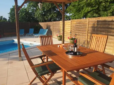 a wooden table with chairs and a bottle of wine at La Pepiniere a beautiful air-con villa with private pool In the canal-side village of Homps in Homps