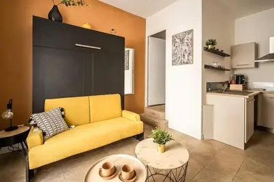 a living room with a yellow couch and a table at Studio narbonne in Narbonne