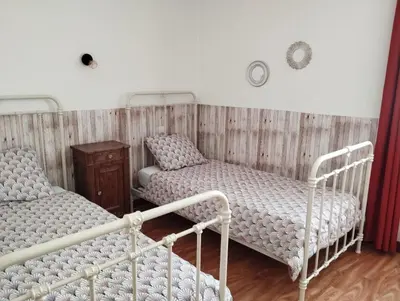 a room with two beds and a wooden wall at Cheminée, jardin et tranquillité assurée in Verdalle