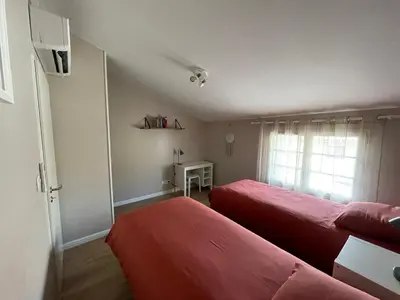 a bedroom with two red beds and a window at Gîte Le Courredou Portel des Corbières in Portel-des-Corbières