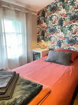 a bedroom with a red bed with a floral wallpaper at Gîte Le Courredou Portel des Corbières in Portel-des-Corbières