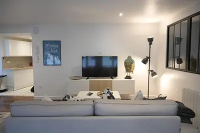 a living room with a white couch and a tv at La Chouette - Atypique & lumineux, Place Jean Jaurès in Castres