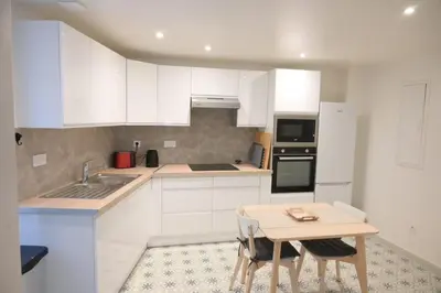 a kitchen with white cabinets and a table with chairs at La Chouette - Atypique & lumineux, Place Jean Jaurès in Castres