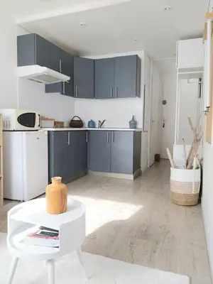 a kitchen with blue cabinets and a white table at Studio cosy avec piscine et parking à Gruissan in Gruissan