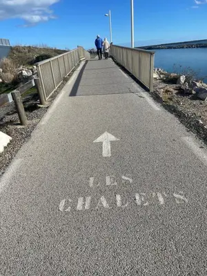 two people walking on a bridge over a body of water at Studio cosy avec piscine et parking à Gruissan in Gruissan