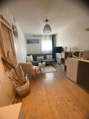 a living room with a couch and a table at Studio cosy avec piscine et parking à Gruissan in Gruissan