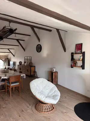a living room with a table and a white chair at La maison au bord de l'Aude in Limoux