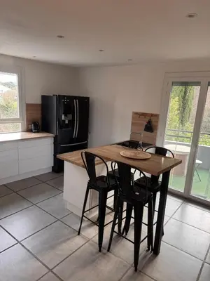 a kitchen with a table and chairs and a refrigerator at La maison au bord de l'Aude in Limoux