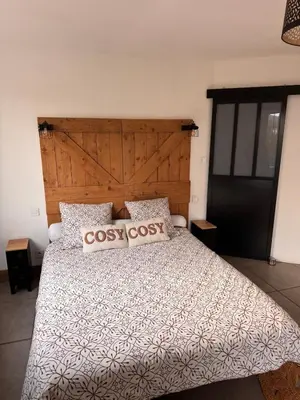 a bedroom with a large bed with a wooden headboard at La maison au bord de l'Aude in Limoux