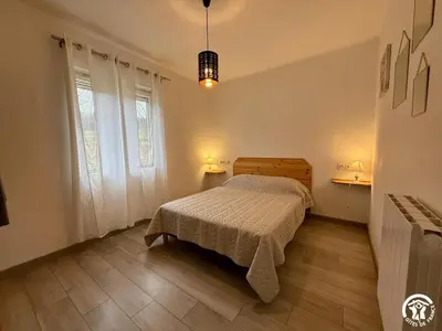 a bedroom with a bed and two windows at Les ferrajals in Rouvenac