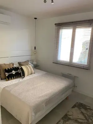 a white bedroom with a bed with pillows and a window at Villa piscine climatisation vue mer pour 8 in Fitou