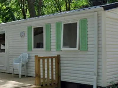 a white house with green shutters and a chair at Mobil home 21m² avec terrasse à Axat - API-1-52-1082 in Axat