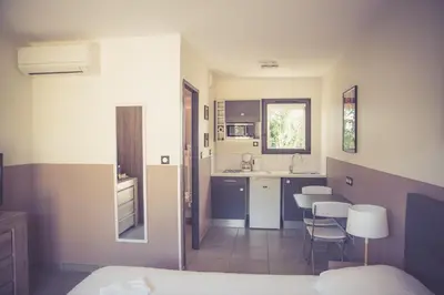 a bedroom with a bed and a kitchen with chairs at 514 Appart Hotel in Carcassonne
