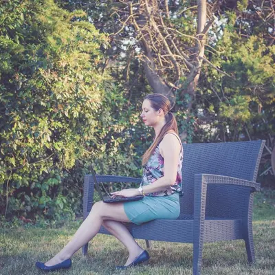 a woman sitting on a bench with a laptop at 514 Appart Hotel in Carcassonne