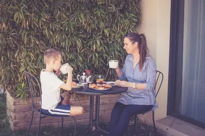 a woman and a boy sitting at a table drinking coffee at 514 Appart Hotel in Carcassonne
