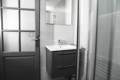 a bathroom with a sink and a mirror and a door at 514 Appart Hotel in Carcassonne