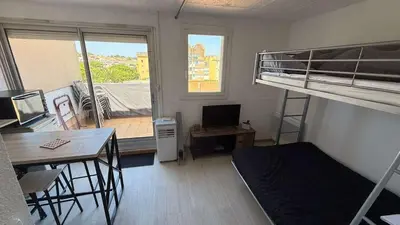 a dorm room with a bunk bed and a desk and a deskablish at AIG168 GRUISSAN STUDIO VUE PORT AVEC TERRASSE PARKING ET PISCINES in Gruissan