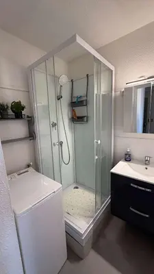 a white bathroom with a shower and a sink at AIG168 GRUISSAN STUDIO VUE PORT AVEC TERRASSE PARKING ET PISCINES in Gruissan