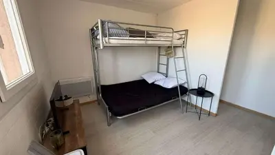 a bedroom with a bunk bed with a black bedsheet at AIG168 GRUISSAN STUDIO VUE PORT AVEC TERRASSE PARKING ET PISCINES in Gruissan