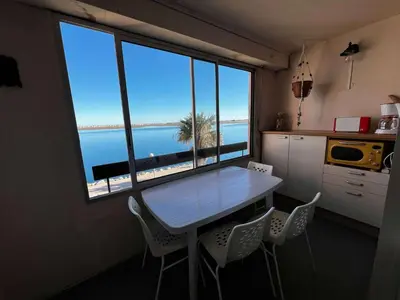 a table and chairs in a kitchen with a view of the ocean at AIG_42 Appartement Type 2 – 4 couchages – Superbe vue avant-port à Gruissan in Gruissan