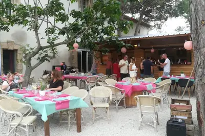a group of tables and chairs with pink and blue tables at Gîte Narbonne 15 personnes in Narbonne