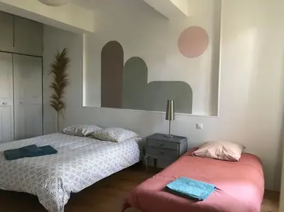 a bedroom with two beds and a table with a lamp at Gîte Narbonne 15 personnes in Narbonne