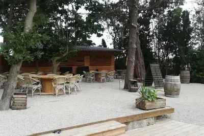 a patio with tables and chairs and a cabin at Gîte Narbonne 15 personnes in Narbonne