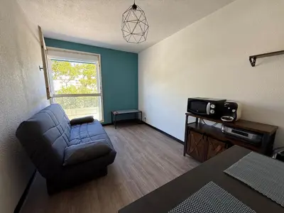 a living room with a couch and a tv at Studio 17 m2 avec piscine et parking - Gruissan in Gruissan
