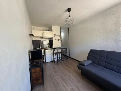 a living room with a couch and a kitchen at Studio 17 m2 avec piscine et parking - Gruissan in Gruissan
