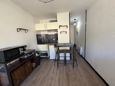 a small kitchen with a bar stool in a small apartment at Studio 17 m2 avec piscine et parking - Gruissan in Gruissan