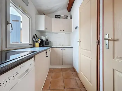 a small kitchen with white cabinets and a window at Villa Closia - Maison de vacances à 50mètres de la plage - Climatisation et Wifi in Gruissan