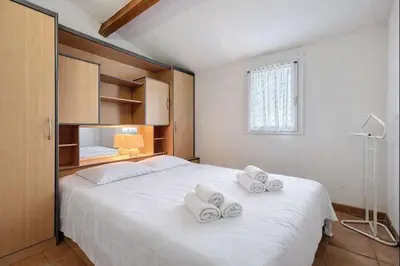 a bedroom with a large white bed with towels on it at Villa Closia - Maison de vacances à 50mètres de la plage - Climatisation et Wifi in Gruissan
