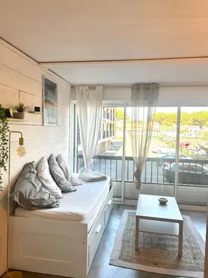 a bedroom with a bed and a large window at Studio chaleureux en bord de mer in Gruissan