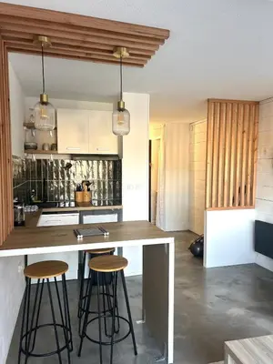 a kitchen with a counter and two bar stools at Studio chaleureux en bord de mer in Gruissan
