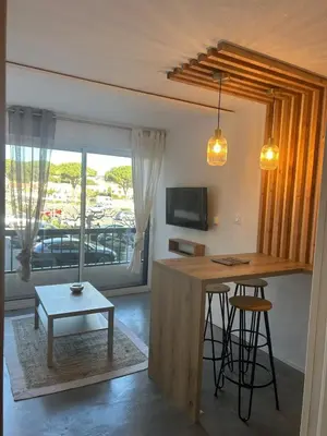 a kitchen with a bar and a table with stools at Studio chaleureux en bord de mer in Gruissan
