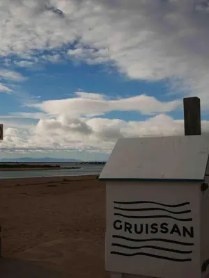 a sign on the beach with the ocean in the background at Studio chaleureux en bord de mer in Gruissan