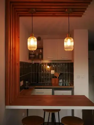 a kitchen with two lights and a counter with stools at Studio chaleureux en bord de mer in Gruissan