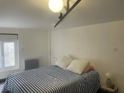 a white bedroom with a bed with a striped blanket at Résidence des catalans in Narbonne
