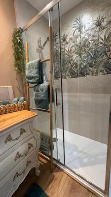 a shower with a glass door with blue towels at L'écrin vert in Villelongue-dʼAude