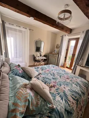 a bedroom with a bed with a floral bedspread at L'écrin vert in Villelongue-dʼAude