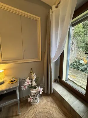 a room with a window with a table and a vase with flowers at L'écrin vert in Villelongue-dʼAude