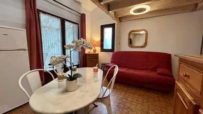 a living room with a table and a red couch at Pavillon avec piscine collective proche Grazel - GN020-001 in Gruissan