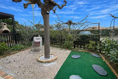 a tree and a chair next to a putting green at Pavillon avec piscine collective proche Grazel - GN020-001 in Gruissan