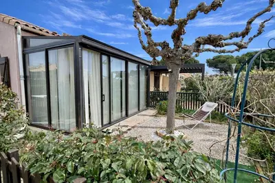a glass house with a tree in a garden at Pavillon avec piscine collective proche Grazel - GN020-001 in Gruissan