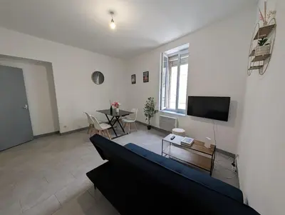a living room with a blue couch and a table at Agréable appartement 65 m2 type 3 Narbonne centre-ville in Narbonne