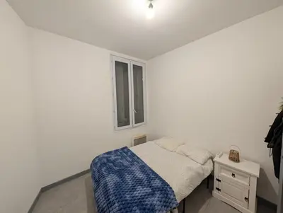 a white bedroom with a bed and a window at Agréable appartement 65 m2 type 3 Narbonne centre-ville in Narbonne